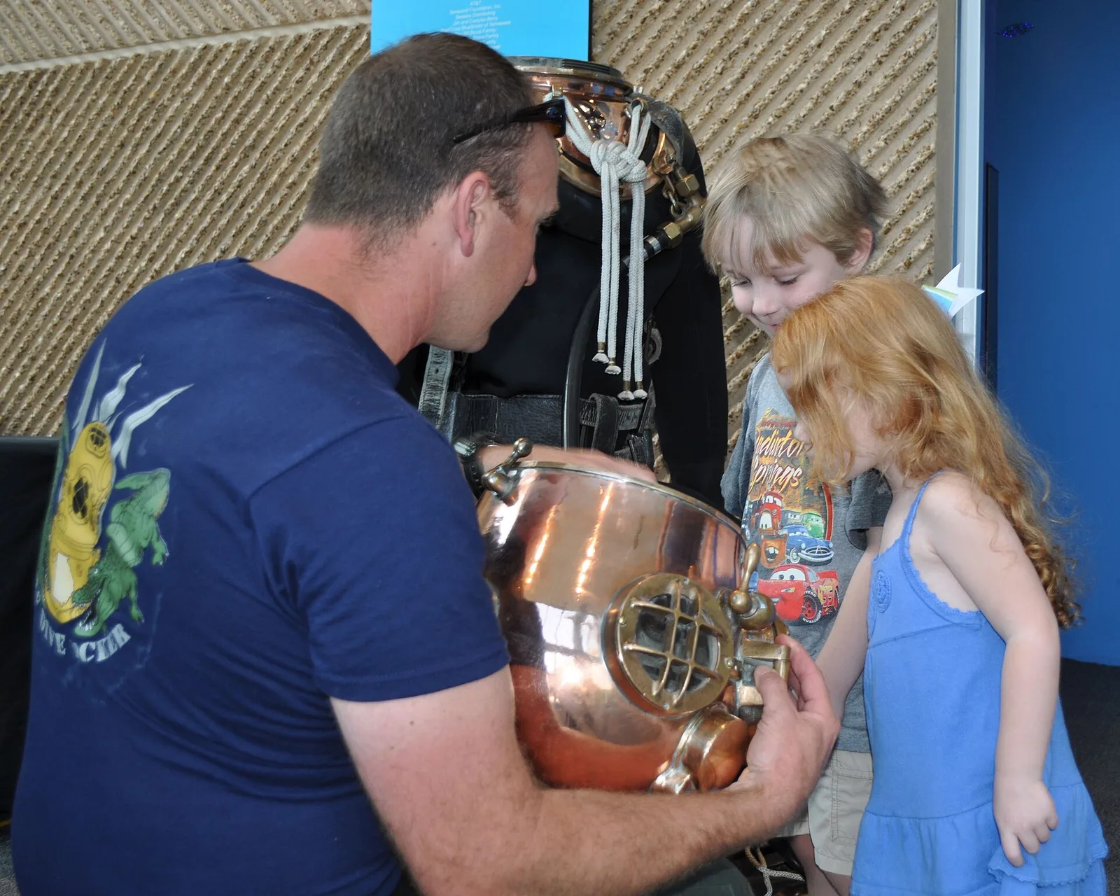 A Navy diver shows children the inside of an old copper diving helmet at the Tennessee Aquarium in Chattanooga.